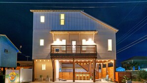 A two-story building with a balcony and outdoor seating area, featuring a sign that reads "Seas the Bay." - Seas The Bay by Avantstay In-town Private Pool (Port Aransas)