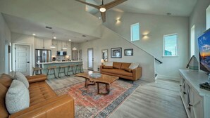 A spacious living area with a sofa, coffee table, and a kitchen in the background. - Seas The Bay by Avantstay In-town Private Pool (Port Aransas)
