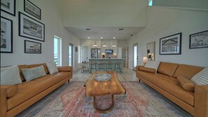 A spacious living room with two leather sofas, a wooden coffee table, and a patterned rug. - Seas The Bay by Avantstay In-town Private Pool (Port Aransas)