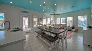 A spacious kitchen with a wooden island, white cabinetry, and a ceiling fan. - Pool Access, Private Patio Living, Near the Beach Seahorse Cove by Avantstay (Port Aransas)