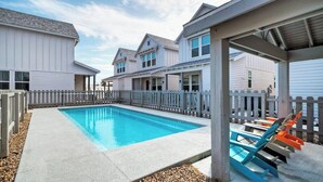 A swimming pool with a wooden deck, a covered seating area, and a white fence. - A Crazy Beach by Avantstay Steps to Old Town (Port Aransas)