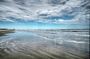 A beach with a wide sandy shore and gentle waves. - Beach Daze by Avantstay 1 Block to Beach (Port Aransas)