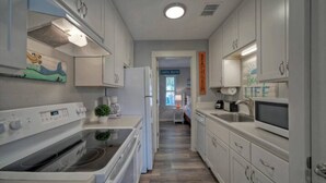 A modern kitchen with white cabinetry, a built-in oven, and a microwave.