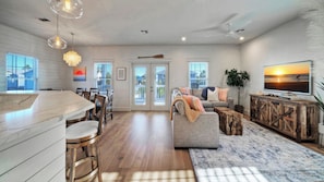 A spacious living area with a dining table, sofa, and TV. - Priv Pool & Yard w/ Putting Green! Newly Remodeled Always Sunny by Avantstay (Port Aransas)
