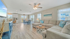A spacious living room with a large sofa, a dining area, and a kitchen.