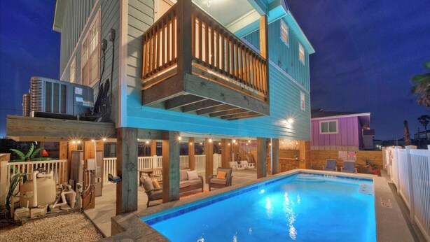Ein zweistöckiges Haus mit Pool, Sitzgelegenheiten im Freien und einer überdachten Terrasse.