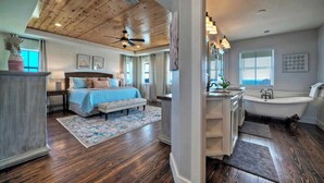 Une chambre spacieuse avec un grand lit, un plafond en bois et une vue sur la salle de bain.