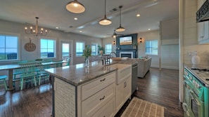 A spacious kitchen with a large island, dining area with chairs, and a view of the outdoors.