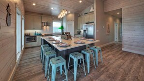 A spacious kitchen with a large island, wooden flooring, and light-colored cabinetry. - Private Pool, Covered Patio 4 Blocks to Beach Bourbon Breeze by Avantstay (Port Aransas)
