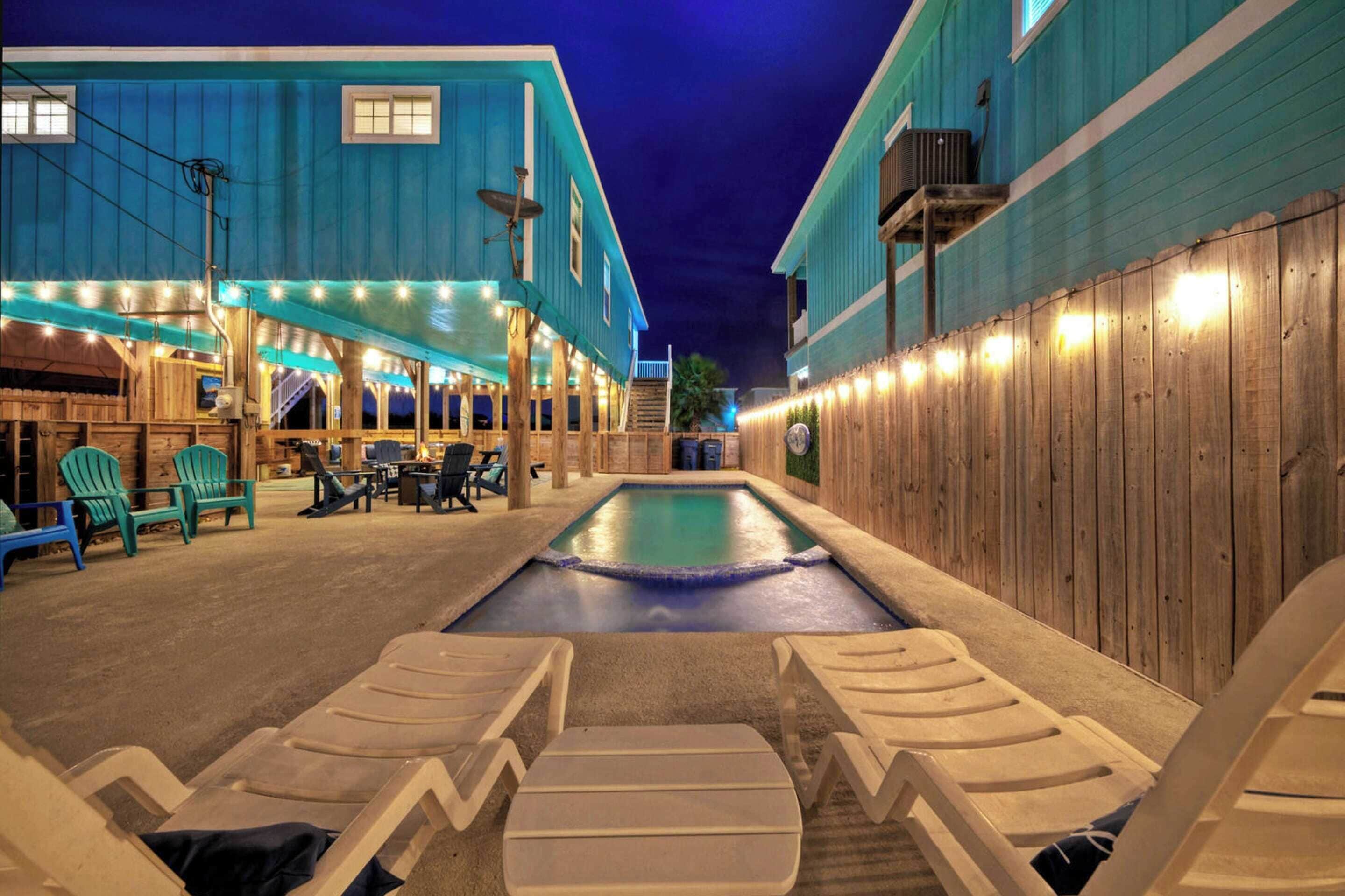 A pool area with lounge chairs and a wooden deck.