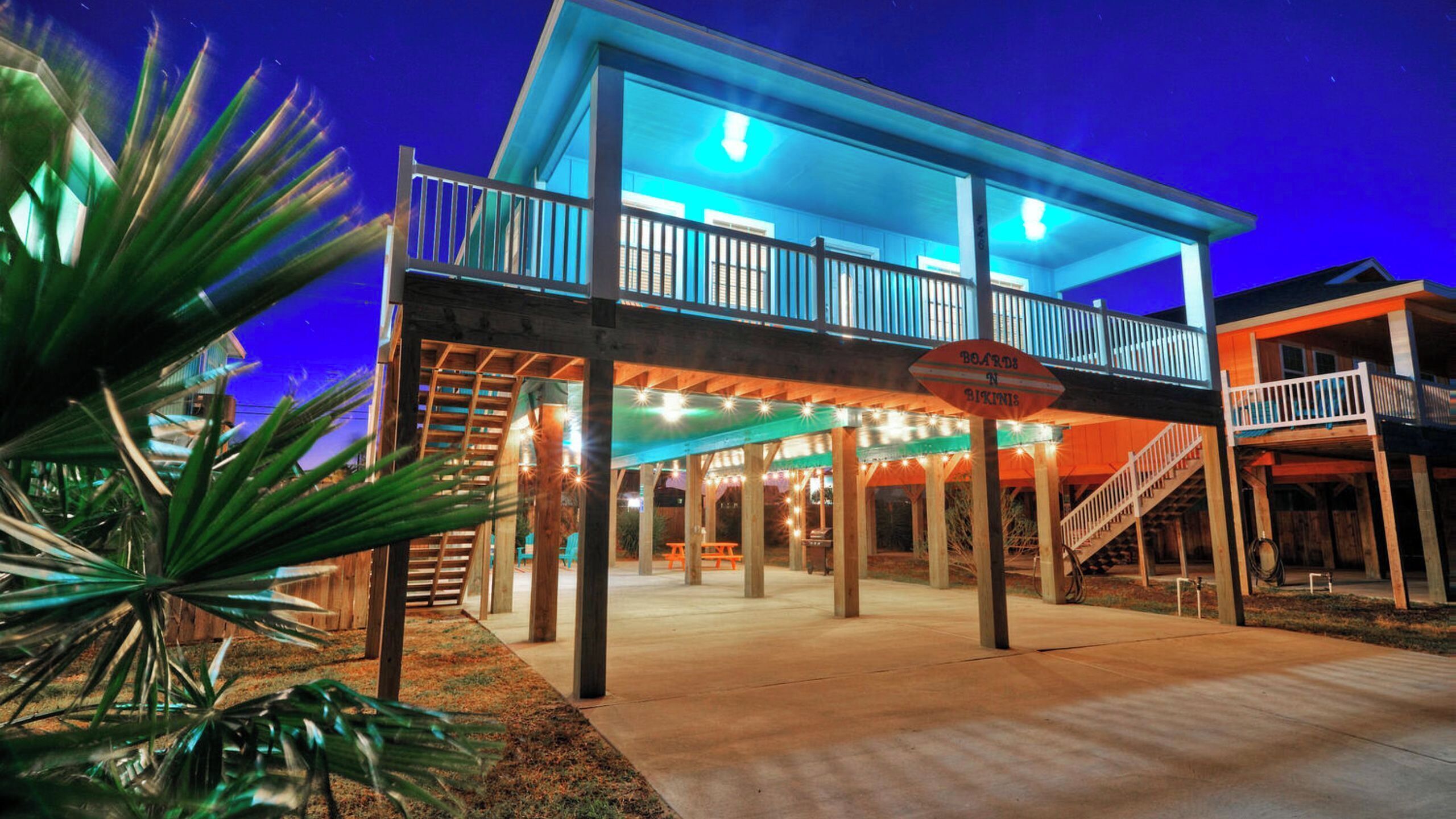 A waterfront building with a balcony, outdoor seating, and a sign indicating a restaurant.