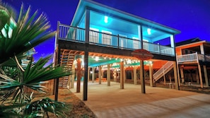 A waterfront building with a balcony, outdoor seating, and a sign indicating a restaurant.