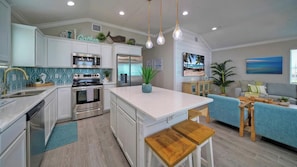A modern kitchen with white cabinetry, stainless steel appliances, and a central island.
