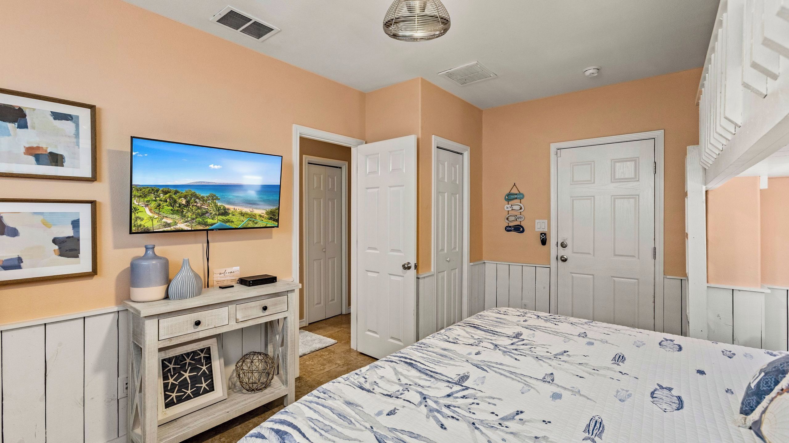 Une chambre à coucher avec un lit, une télévision, une commode et une porte.