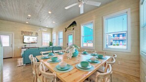 A dining area with a wooden table set for six, surrounded by six chairs. - Backyard Tiki Bar, Walk to the Beach, Pool Cabana Cheeky Tiki by Avantstay (Port Aransas)