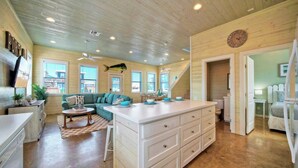 A spacious kitchen with a large island, wooden ceiling, and a view of the outside. - Backyard Tiki Bar, Walk to the Beach, Pool Cabana Cheeky Tiki by Avantstay (Port Aransas)