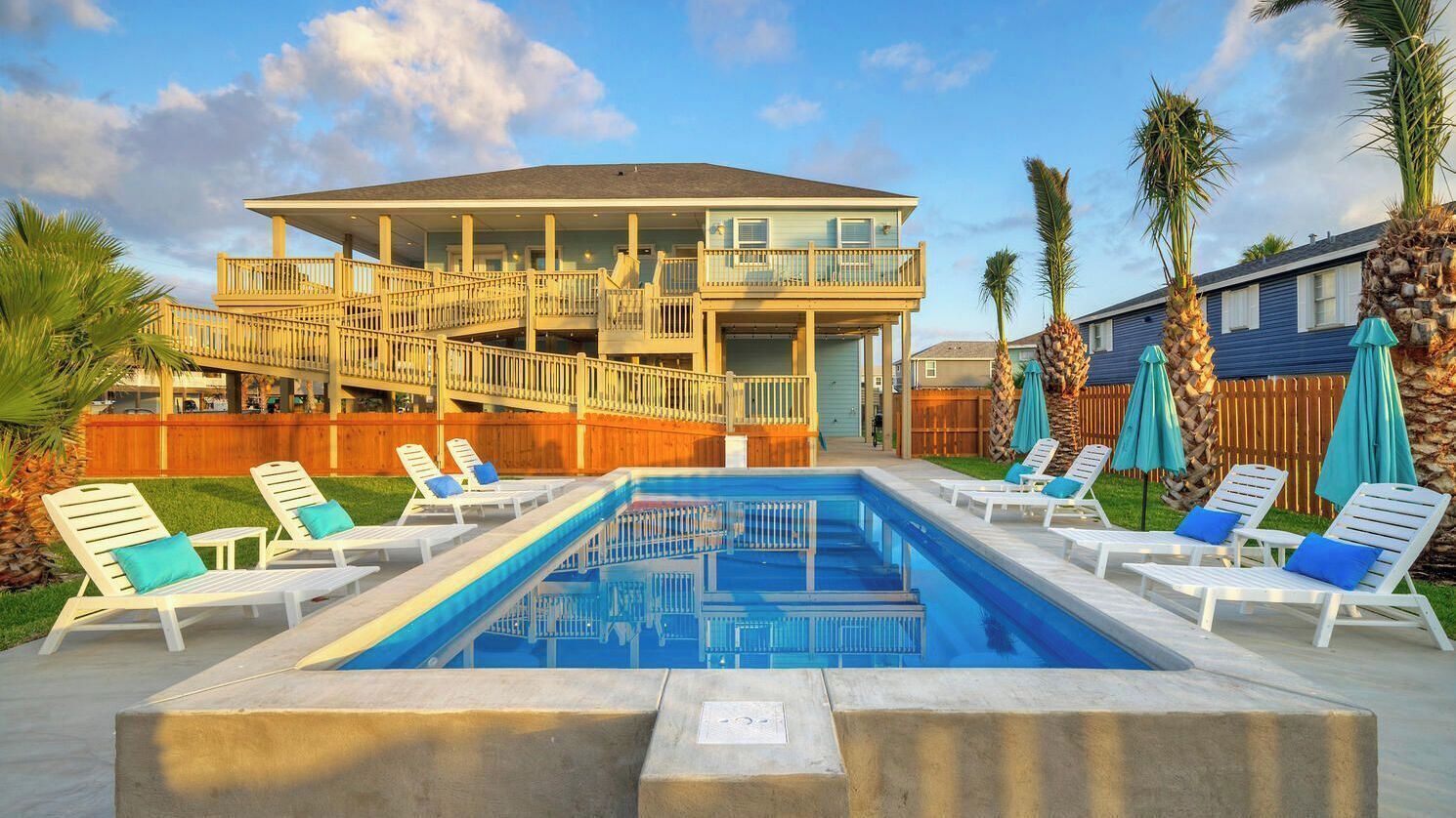 Un espace piscine avec des chaises longues et un bâtiment à deux étages doté de balcons.