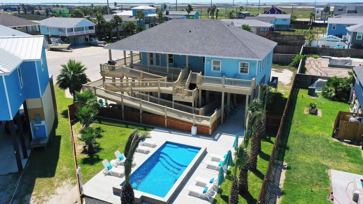 A large house with a swimming pool, a covered deck, and a fenced yard.