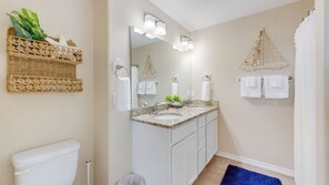 Une salle de bain avec des toilettes, un meuble-lavabo à deux vasques et un grand miroir.