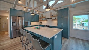 Una cocina moderna con gabinetes color aguamarina, electrodomésticos de acero inoxidable y una isla grande con taburetes de bar.