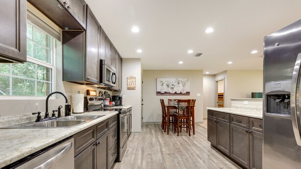A modern kitchen with dark wooden cabinets, stainless steel appliances, and a granite countertop. - Rural Retreat w/ Covered Porch Near Jackson (Grove Hill)