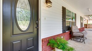 A front door with a glass panel, a potted plant, and a chair on the porch. - Rural Retreat w/ Covered Porch Near Jackson (Grove Hill)