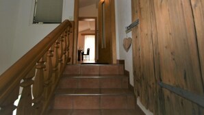 A wooden staircase with a handrail, leading to a room with a dining table and chairs. - Apartment Franz by Interhome (Hippach)