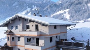 A multi-story building with balconies, a garage, and a view of snow-covered mountains. - Apartment Franz by Interhome (Hippach)
