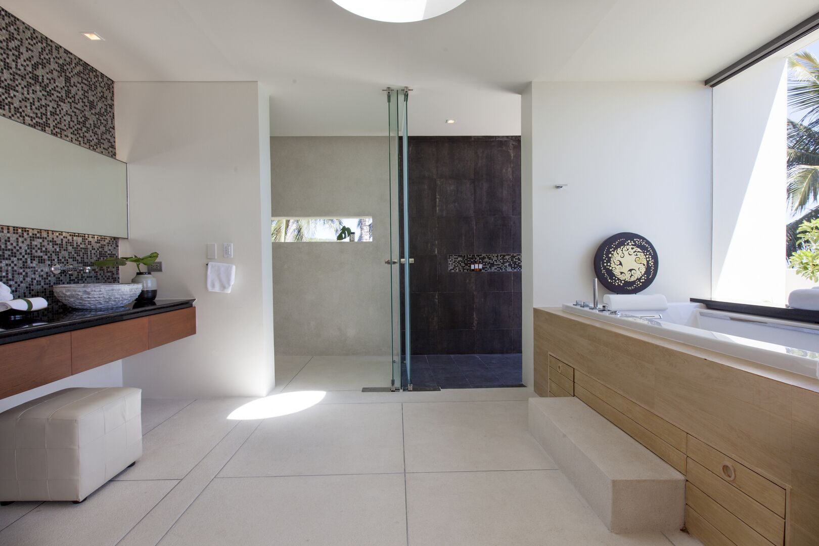 Un baño moderno con mampara de vidrio, un espejo grande y un mueble de tocador de madera.