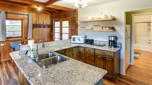 Una cocina con encimeras de granito, armarios de madera, microondas y cafetera.