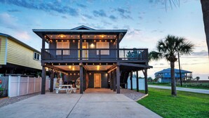 A two-story house with a balcony and a covered patio area. - Boujee Pelican by Avantstay Pool+game Room+views (Port Aransas)