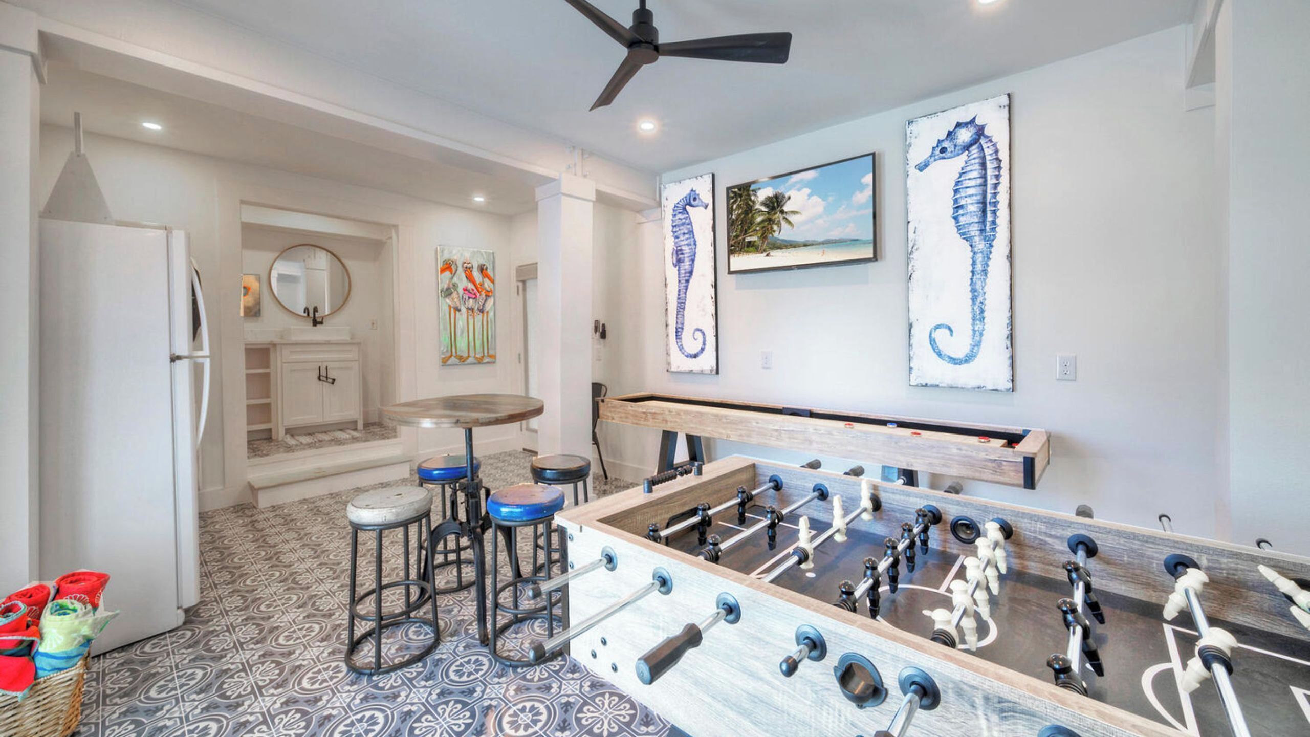 A kitchen with a foosball table, a ceiling fan, and artwork on the walls.