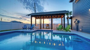 A swimming pool with a covered patio area, outdoor chairs, and a grill. - Boujee Pelican by Avantstay Pool+game Room+views (Port Aransas)