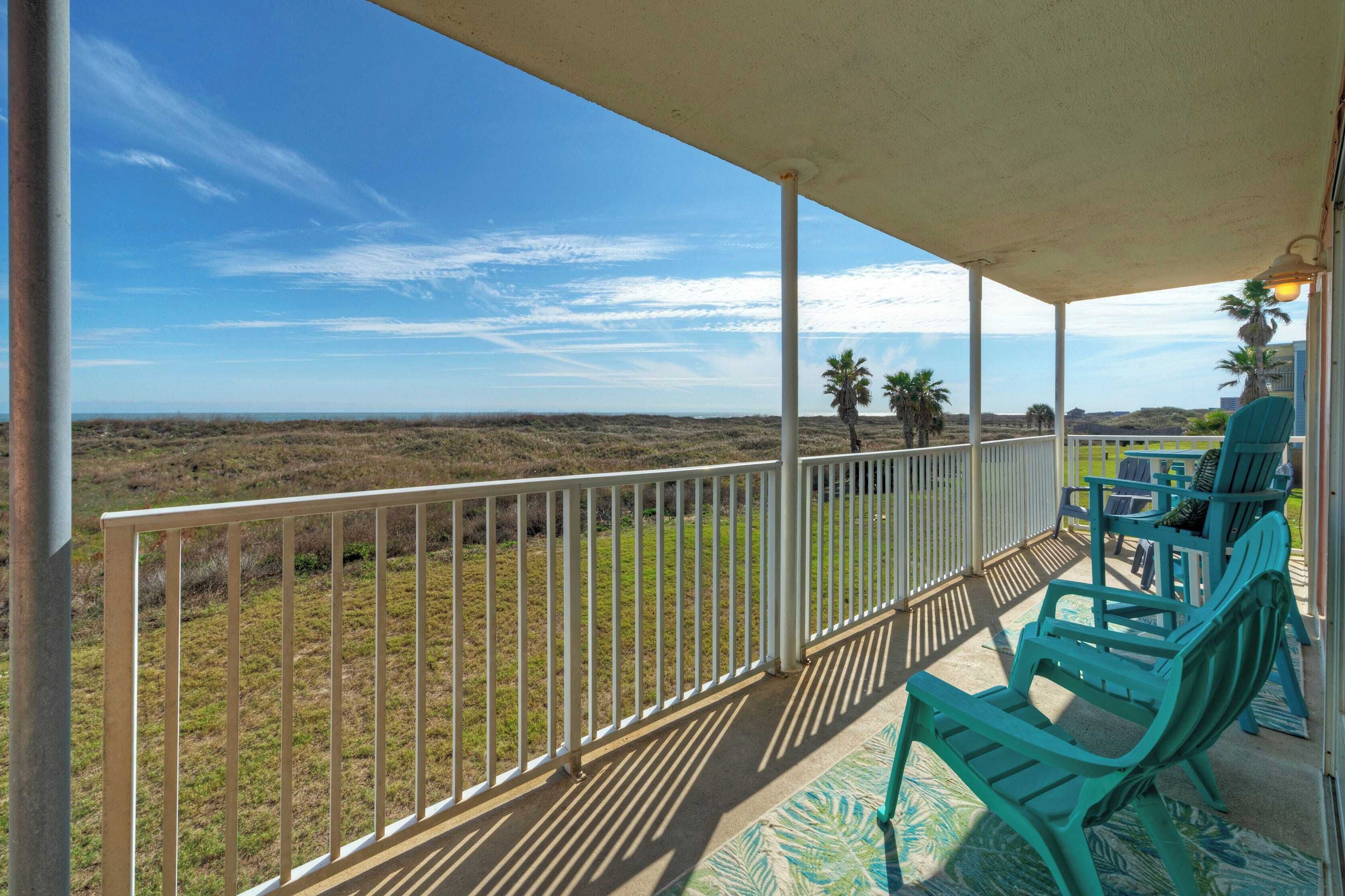 A covered balcony with a view of a grassy landscape and distant mountains.
