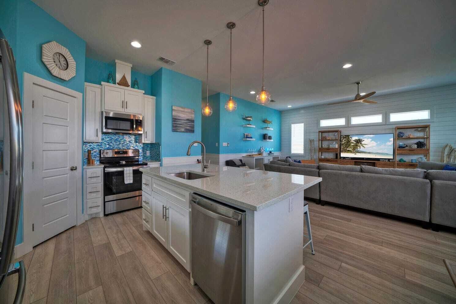 A modern kitchen with a central island, white cabinetry, and a blue accent wall.