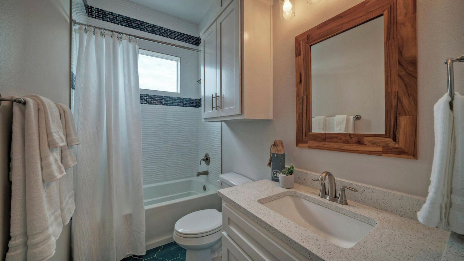 Ein Badezimmer mit Badewanne, Toilette, Waschbecken und Spiegel.