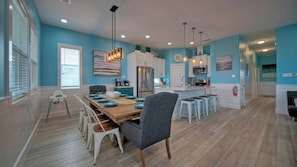 Una cocina moderna con comedor, que incluye una mesa de madera, sillas y taburetes de bar.