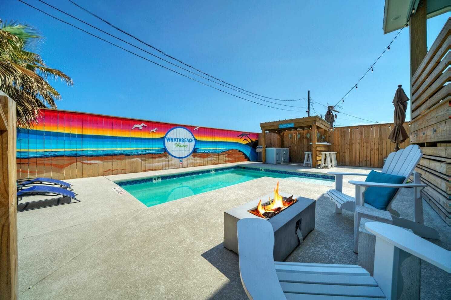 A backyard with a swimming pool, outdoor seating, and a mural of a beach scene.