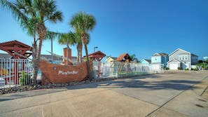A coastal-themed area with a large ship sculpture labeled 'Pirates Bay,' surrounded by residential houses and a fenced playground.