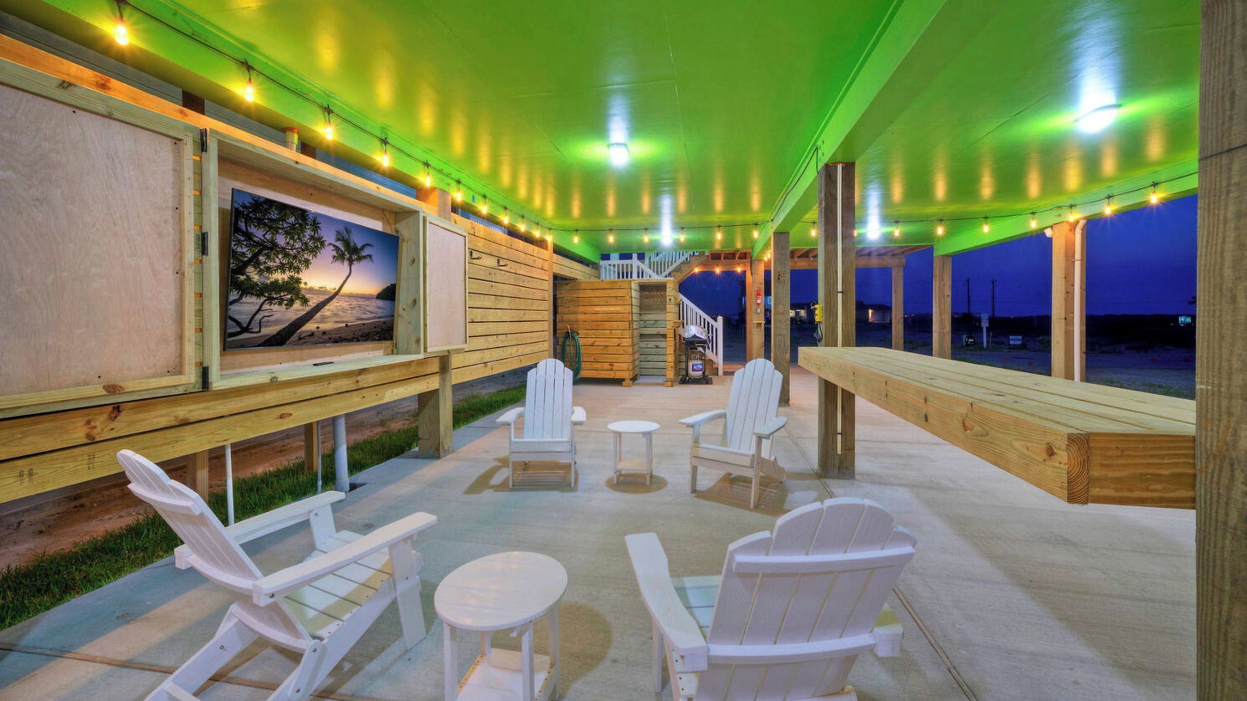 An outdoor patio with Adirondack chairs, a small table, and a wooden deck.
