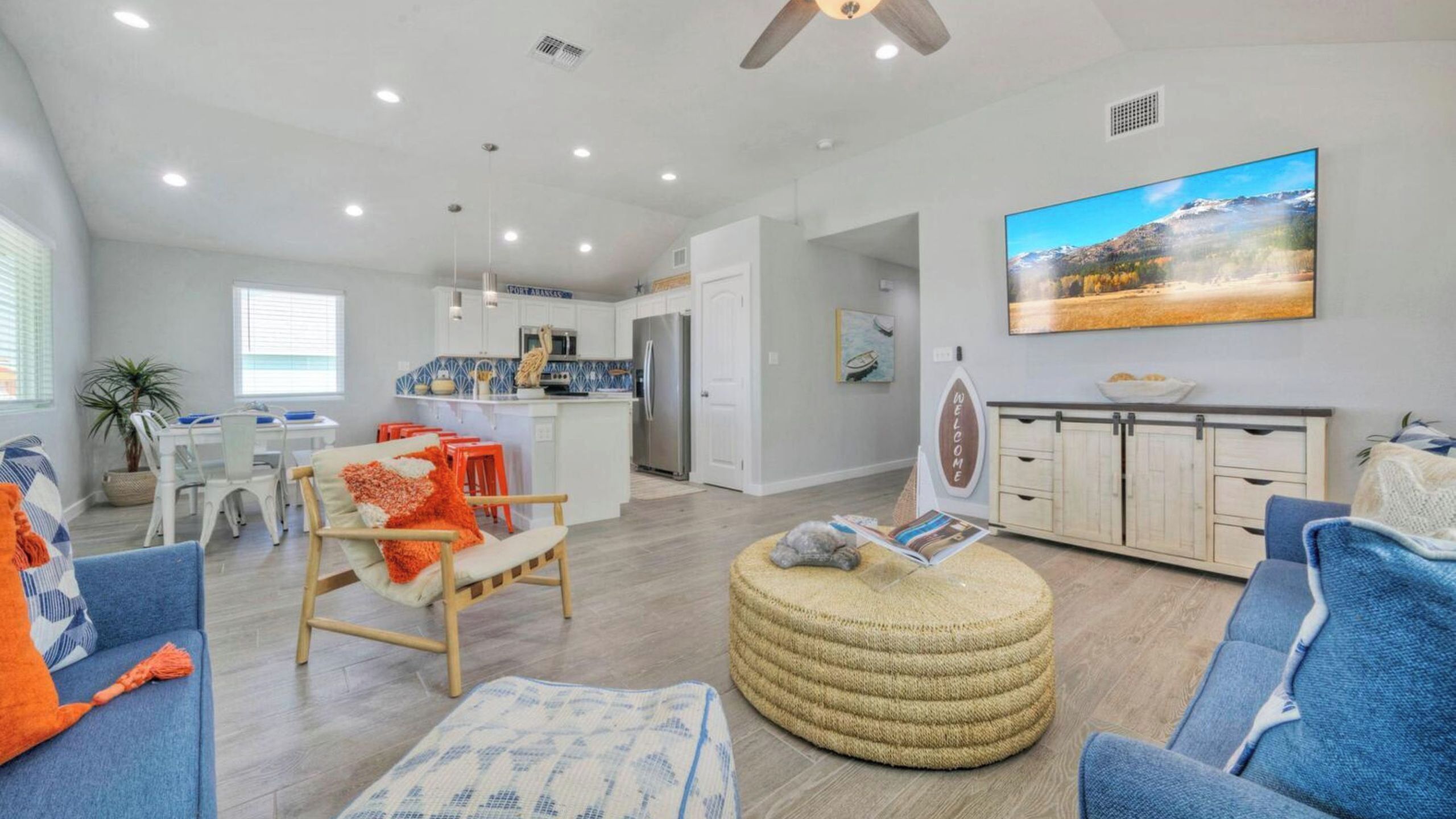 A spacious living area with a kitchen, dining table, and a large painting on the wall.