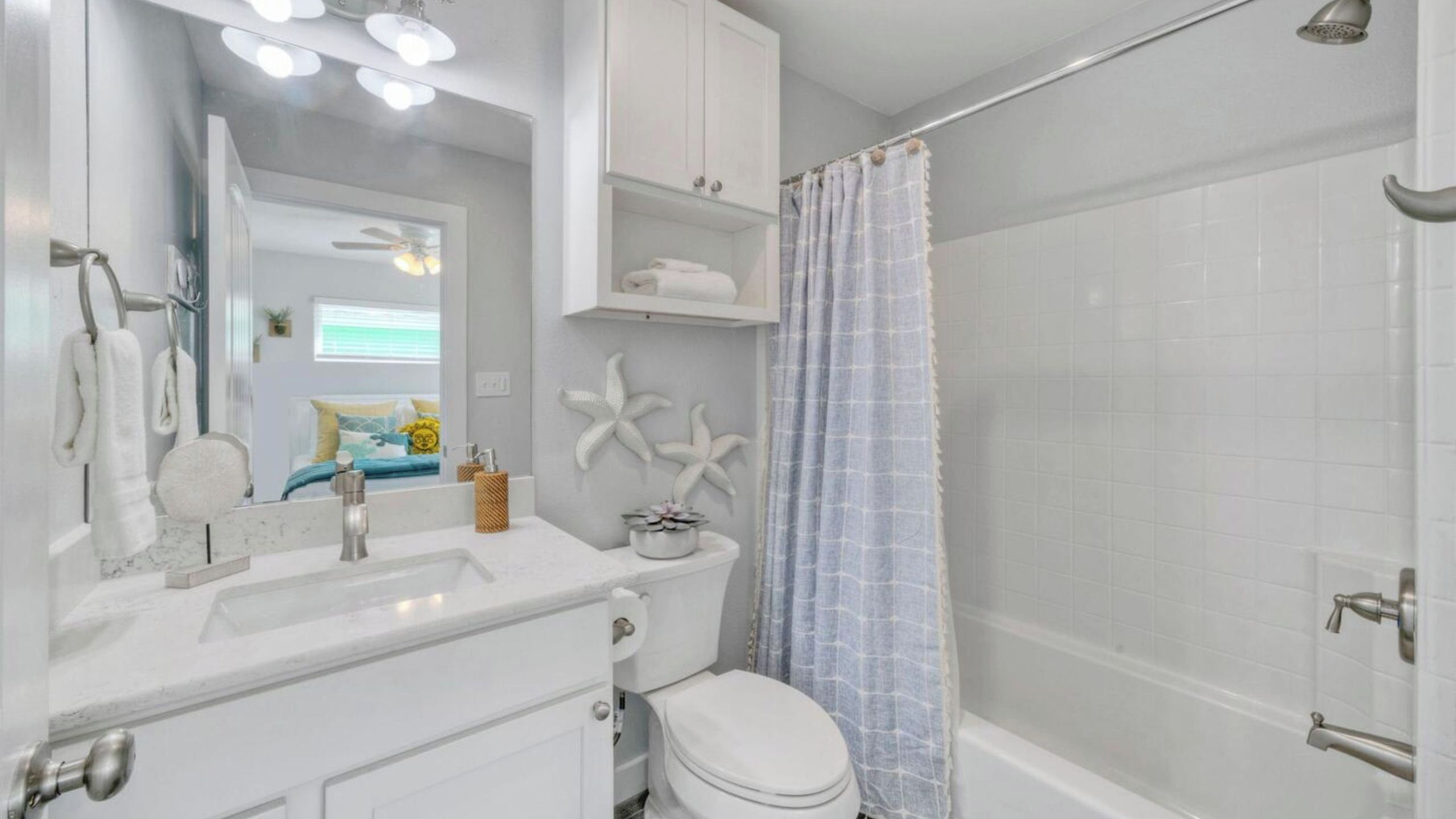 A bathroom with a shower, toilet, sink, and mirror.