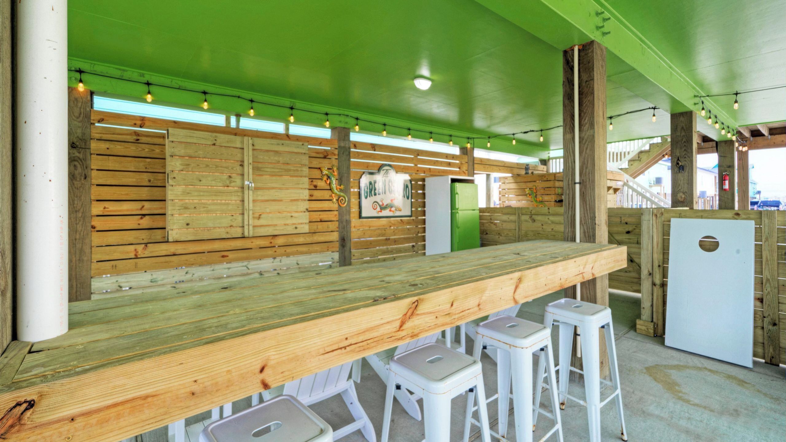 Eine Holztheke mit Hockern, eine grüne Decke und ein Schild mit der Aufschrift 'The Green Room'.