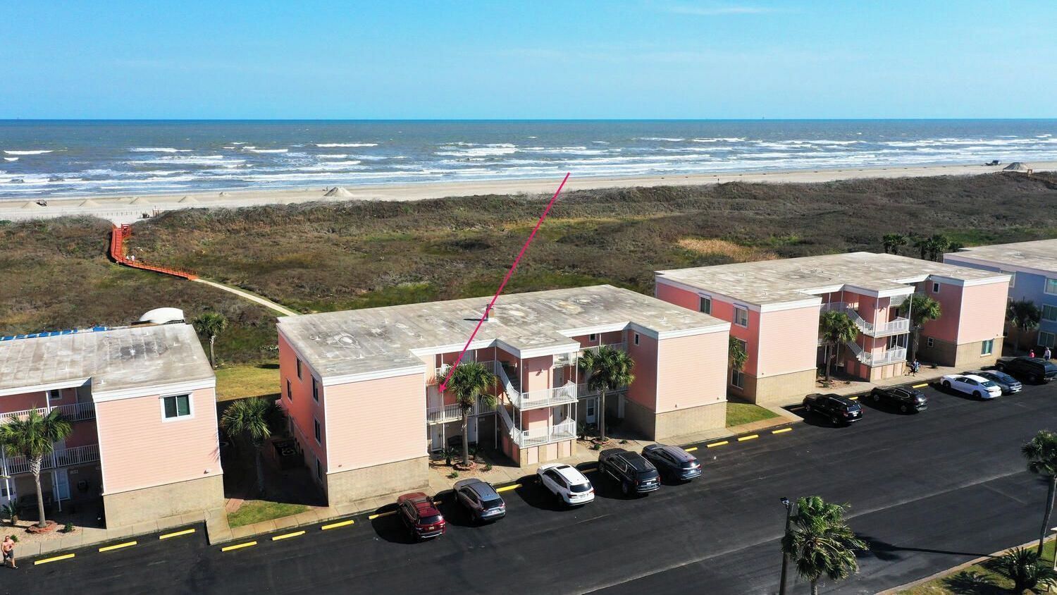 Een hotel aan het strand met meerdere gebouwen, een parkeerplaats en uitzicht op de oceaan.
