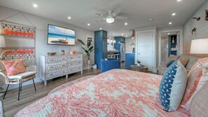 A bedroom with a bed, a chair, a dresser, a ceiling fan, and a wall-mounted TV. - Ocean View w/ Pool, Tennis/pickleball, Beach Access Summer Love by Avantstay (Port Aransas)