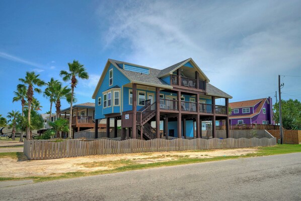 A two-story house with a balcony and a wooden fence. - Incredible Nature Views, Golf Cart for Rent, Balcony Blue Crush by Avantstay (Port Aransas)