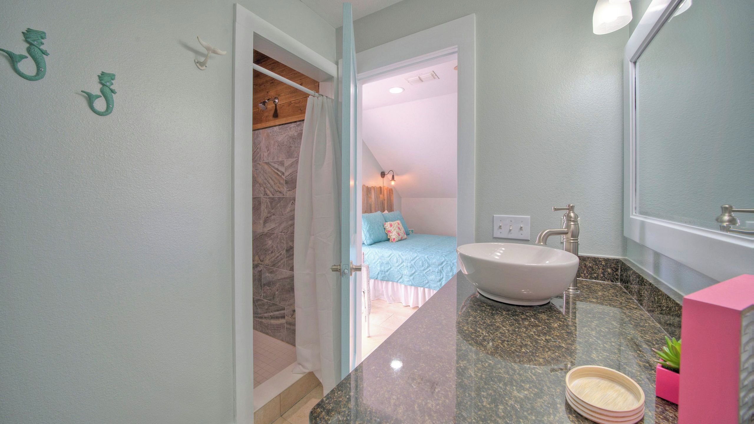 Un baño con lavamanos, espejo y zona de ducha.