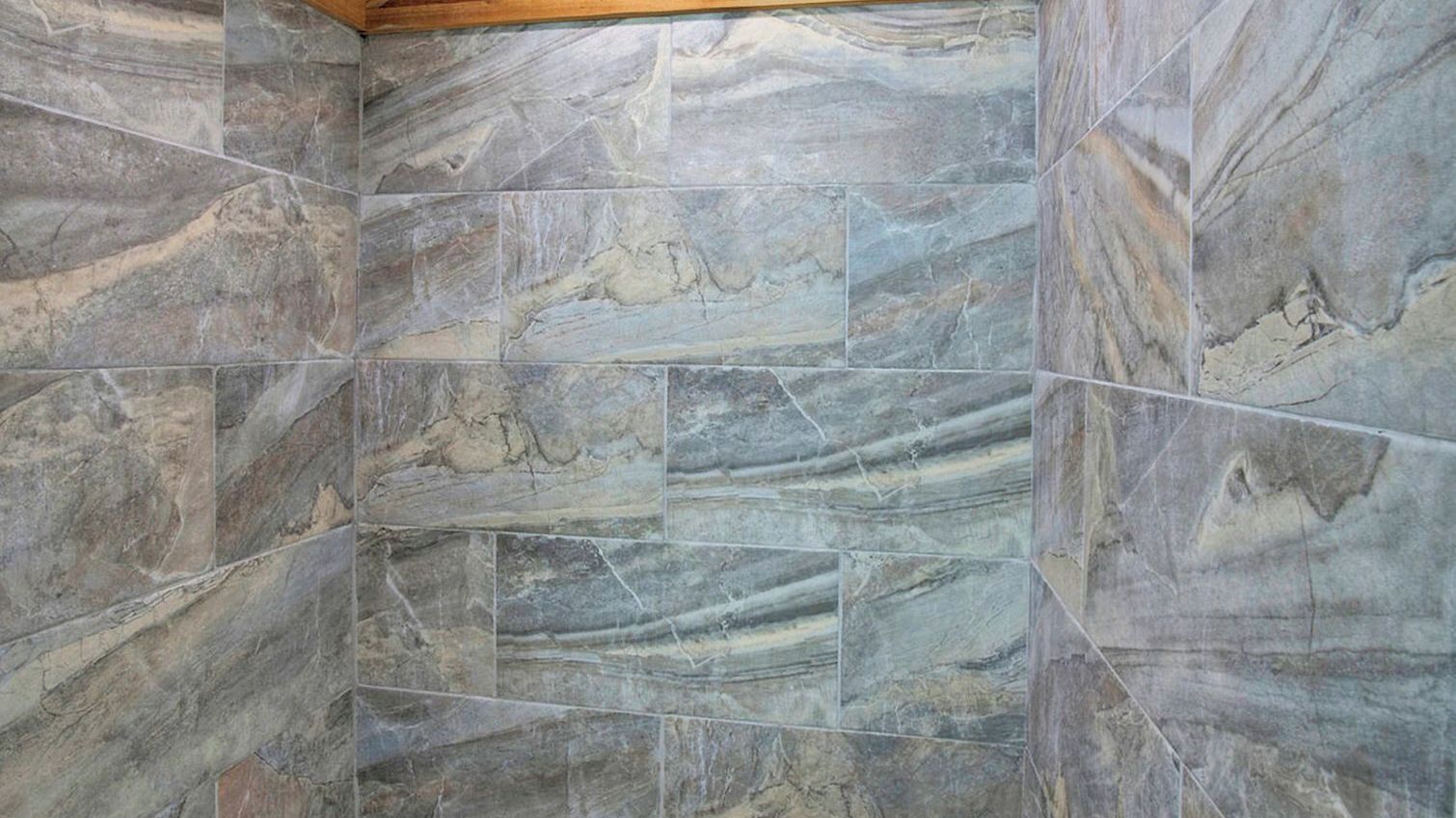 A bathroom with marble tiles and a wooden ceiling.
