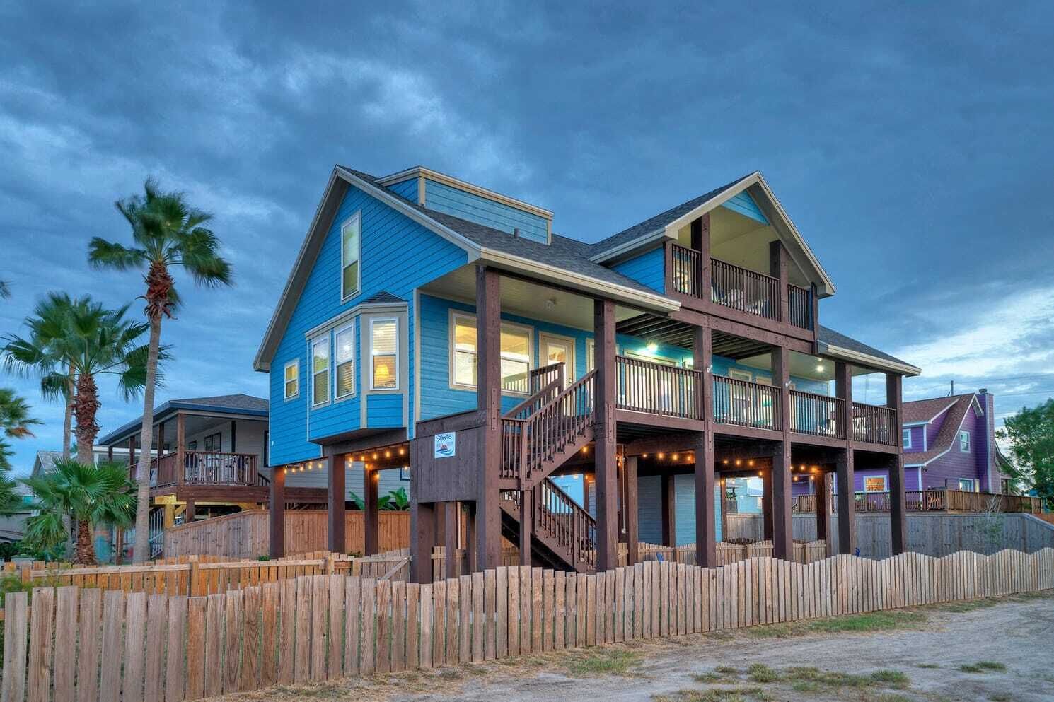 Ein zweistöckiges Haus mit einer Holzterrasse und einer Treppe, die zu der oberen Etage führt.