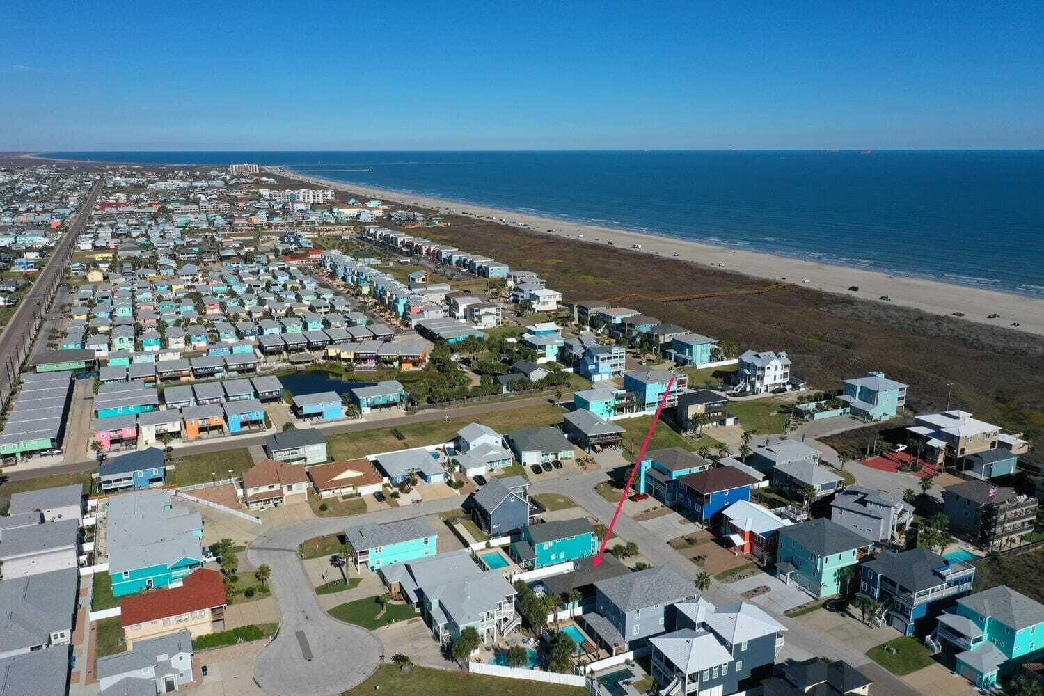 A coastal residential area with houses arranged in rows along the beachfront, featuring a mix of single and multi-story buildings.